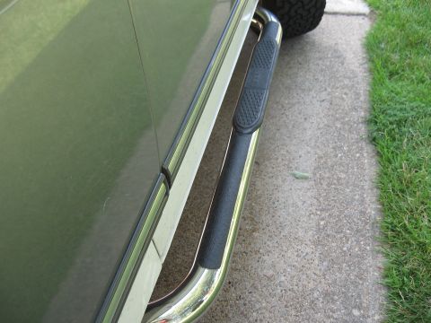 1994 Ford Bronco - Nerf bars are visible on the side of a vehicle, mounted below the door.