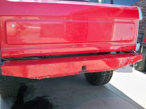 1985 Ford Bronco - Close-up view of the rear of a red vehicle, showing the bumper and lower tailgate area.