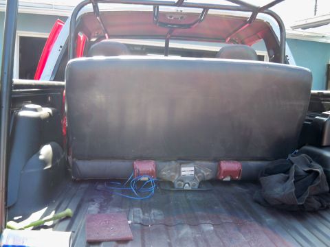 1985 Ford Bronco - The rear interior of a vehicle is visible, including a bench seat and trailer hitch assembly.