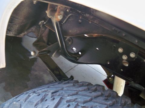 1985 Ford Bronco - Detail shot of the undercarriage, showing suspension components and a tire.