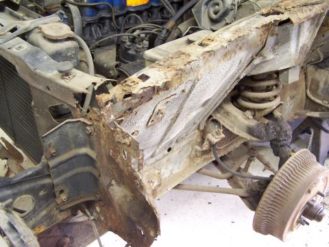 1972 Ford Mustang - Front section of a 1972 Ford Mustang showing extensive rust damage to the frame rail and surrounding components.
