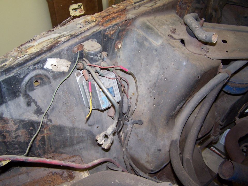 close-up of rusty engine bay with voltage regulator and wiring