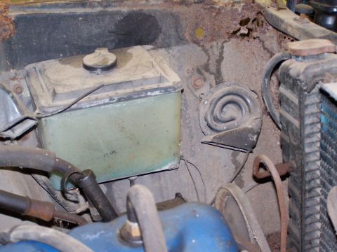 1972 Ford Mustang - The engine bay shows a coolant reservoir, horn, and radiator, with visible rust and wear.