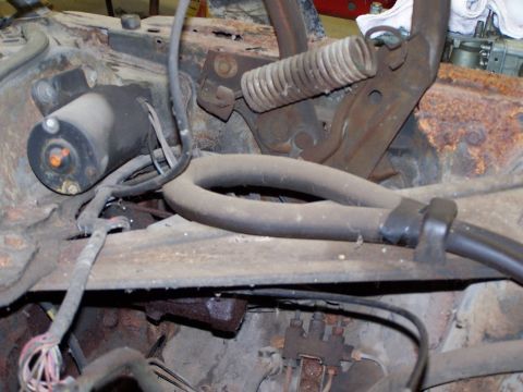 1972 Ford Mustang - Close-up view of engine bay components, including a starter motor and various hoses, showing signs of wear and tear.