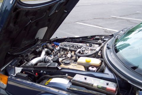 2001 Ford Crown Victoria - The open hood reveals the engine bay of a dark-colored vehicle, with various mechanical parts and wiring visible.
