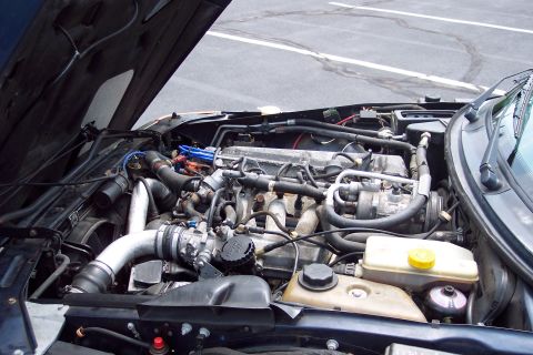 2001 Ford Crown Victoria - The engine compartment of a vehicle is shown with the hood raised, revealing various mechanical parts and wiring.