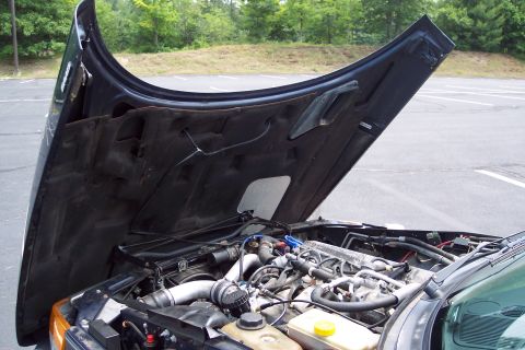 2001 Ford Crown Victoria - The engine bay of a vehicle is exposed with the hood raised, revealing the engine and surrounding parts.