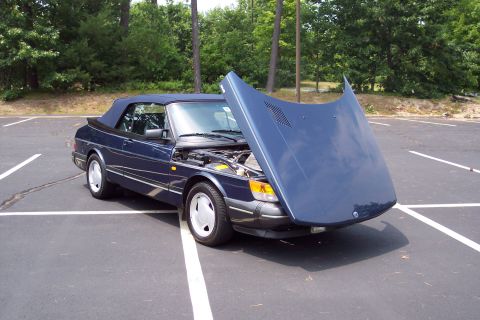 2001 Ford Crown Victoria - A dark blue 1992 Saab 900 Turbo Convertible is parked in a lot with its hood open, revealing the engine compartment.