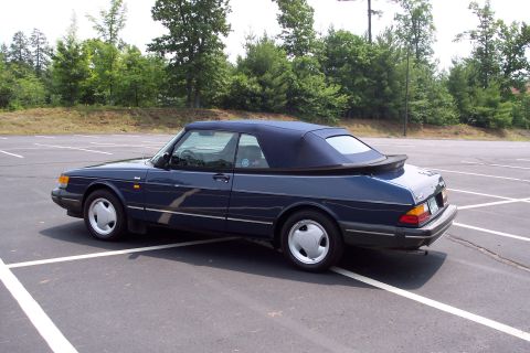 2001 Ford Crown Victoria - A dark blue convertible is parked in an empty lot on a sunny day.