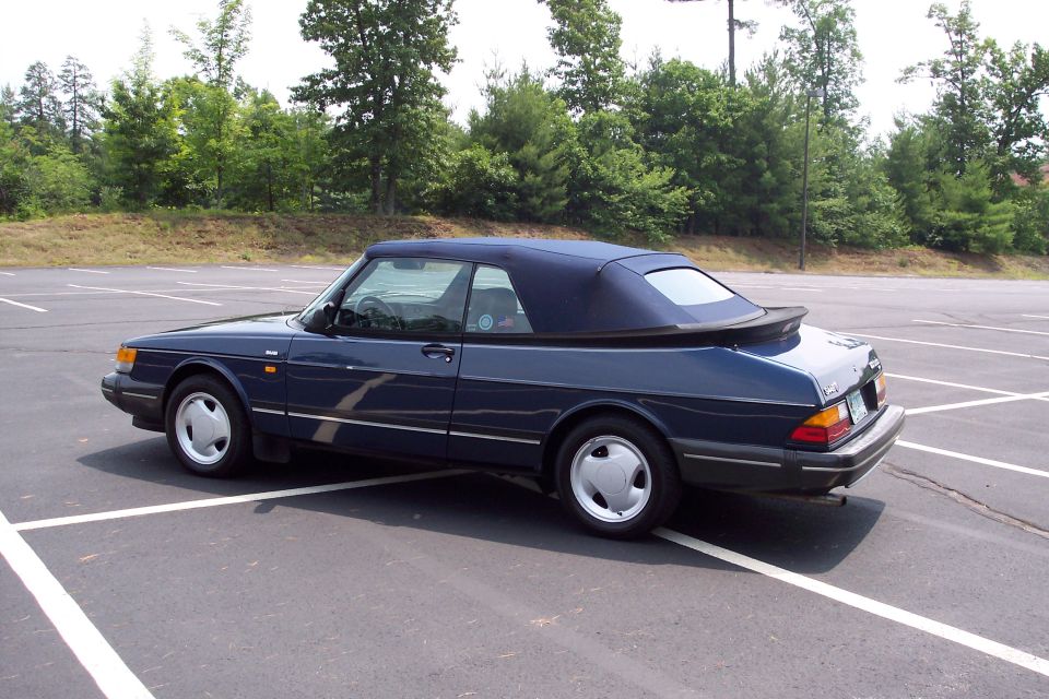 Dark blue convertible parked in an empty lot, rear quarter view