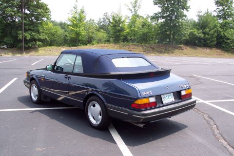 2001 Ford Crown Victoria - A blue Saab 900 Turbo convertible is parked in an empty lot on a sunny day.
