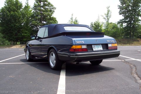 2001 Ford Crown Victoria - Rear view of a dark blue convertible parked in a lot, with trees in the background.