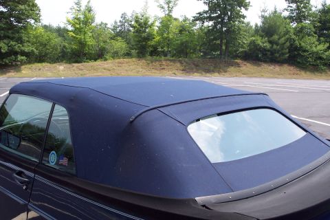 2001 Ford Crown Victoria - Side view of a dark blue convertible with a visible American flag sticker on the window.
