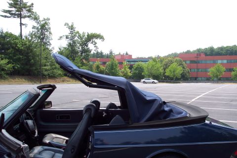 2001 Ford Crown Victoria - Interior view of a dark blue convertible with its top partially retracted, a white car is visible in the background parking lot.