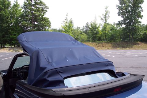2001 Ford Crown Victoria - The blue convertible top of a car is partially raised, obscuring most of the vehicle's details.