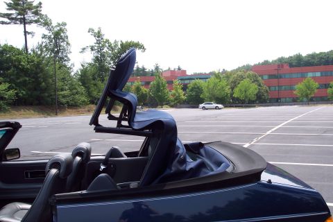 2001 Ford Crown Victoria - The convertible top mechanism is partially raised on a dark blue convertible parked in an empty lot.