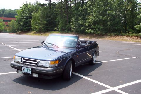 2001 Ford Crown Victoria - A dark blue convertible is parked in an empty lot with trees in the background.