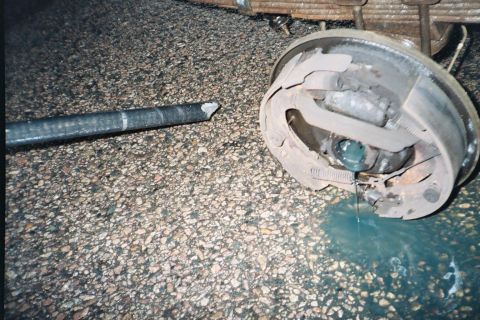1994 Ford Bronco - The vehicle's axle appears to have snapped, and fluid is leaking from the brake system.