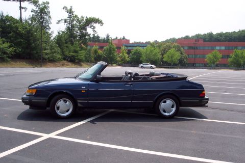 2001 Ford Crown Victoria - A dark blue convertible is parked in a large, empty parking lot with a white car in the background.
