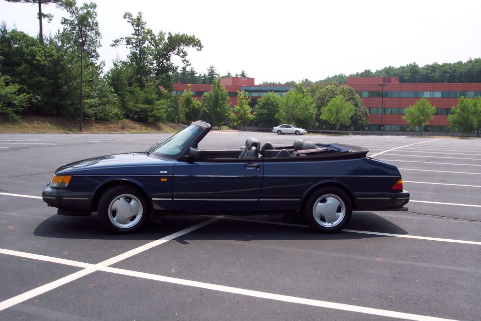 Dark blue convertible parked in an empty lot, side view