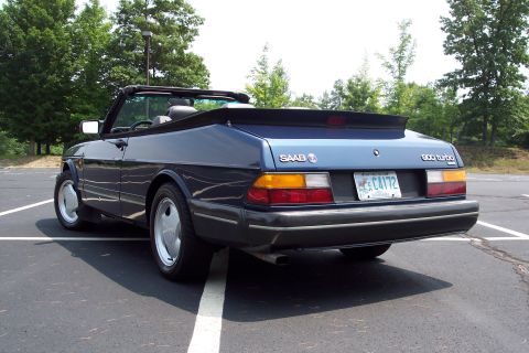 2001 Ford Crown Victoria - Rear view of a blue Saab 900 Turbo convertible parked in a lot with trees in the background.