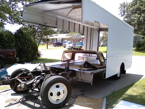 1990 Ford Bronco - A white box truck being parted out in a driveway, with the front cab and nose removed and the entire front section of the box wall cut away…