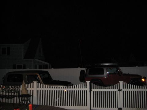 2005 Jeep Wrangler - Two Jeep Wranglers parked in a yard at night, one dark and one red/silver with a roof rack.