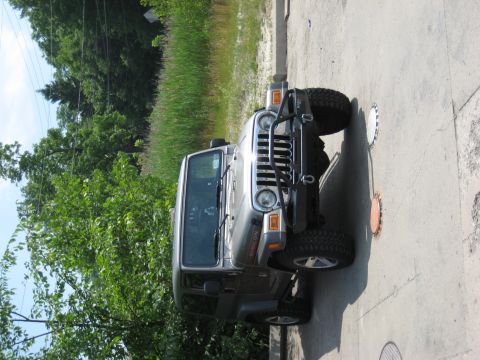 2005 Jeep Wrangler - A silver Jeep Wrangler Rubicon is parked on a paved surface next to a grassy area.