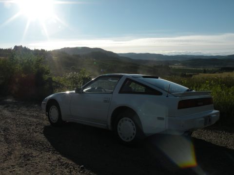 1989 Nissan 300ZX - A white 1989 Nissan 300ZX is parked on a dirt road with a scenic view of hills under a bright sun.