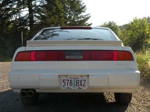 1989 Nissan 300ZX - The rear of a white 1989 Nissan 300ZX is shown, its distinctive taillights and dual exhaust pipes.