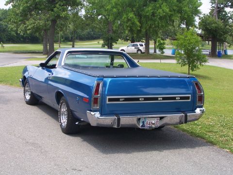 1973 Ford Ranchero - The rear view of a blue Ford Ranchero shows its distinctive taillights and chrome bumper, with a white SUV in the background.