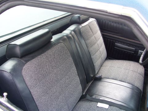 1973 Ford Ranchero - The interior of the vehicle features patterned fabric seats and black vinyl trim, with visible seatbelts.