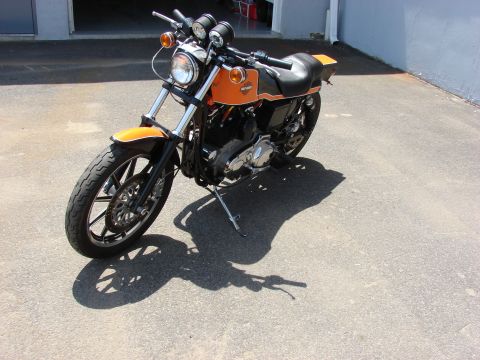 1993 Jeep YJ - A motorcycle with orange and black paint is parked on a paved surface, casting a shadow.