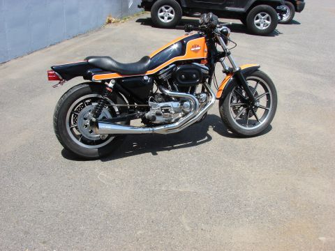 1993 Jeep YJ - A Harley-Davidson Sportster motorcycle is parked on asphalt, with two SUVs in the background.