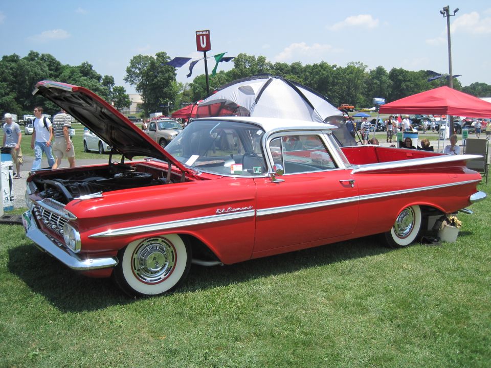 Red and white 1959 Chevrolet El Camino with hood open, parked on grass