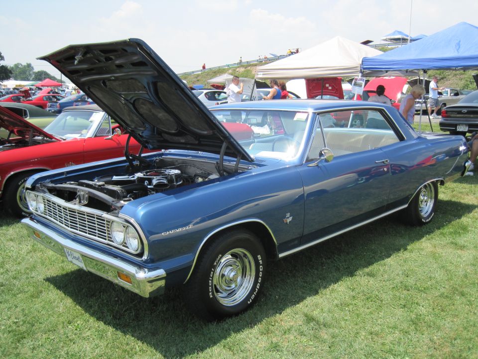 Blue 1964 Chevrolet coupe with hood open, showing engine. Seen at car show