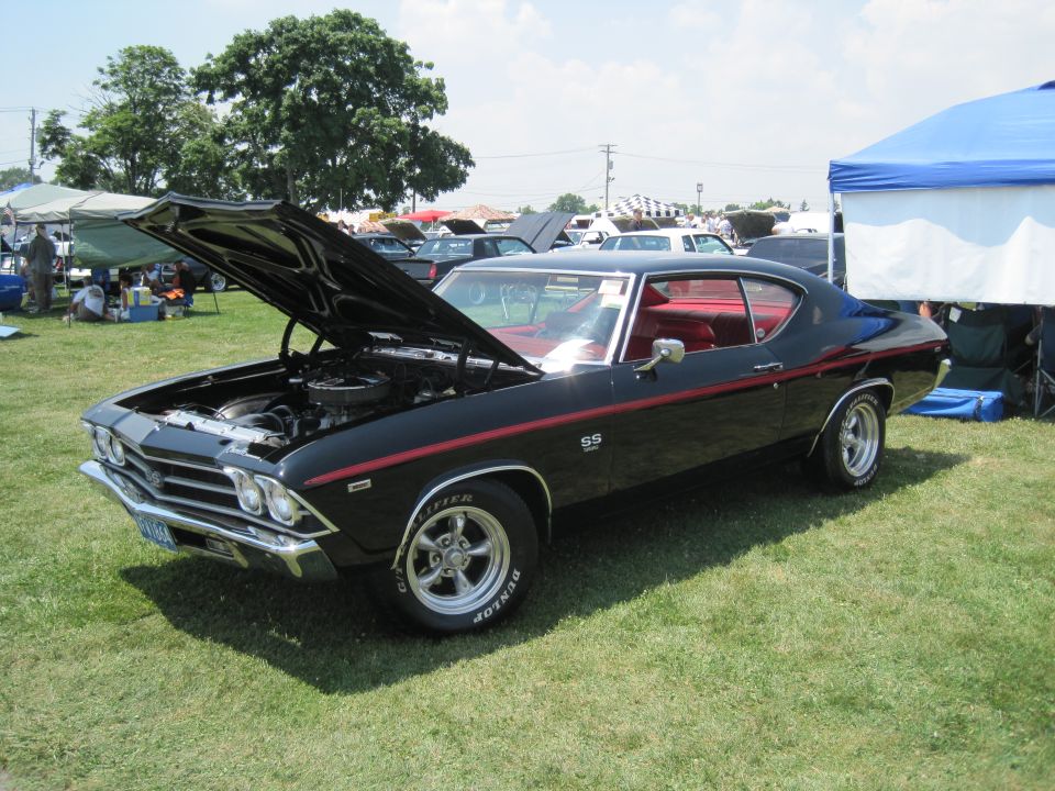 Black 1969 Chevrolet Chevelle SS with red interior, hood open showing engine. Red stripe along the side