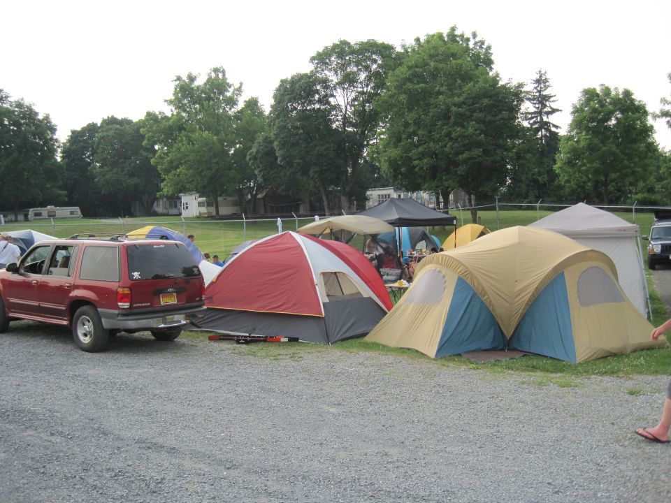 Red SUV parked next to tents at a campsite