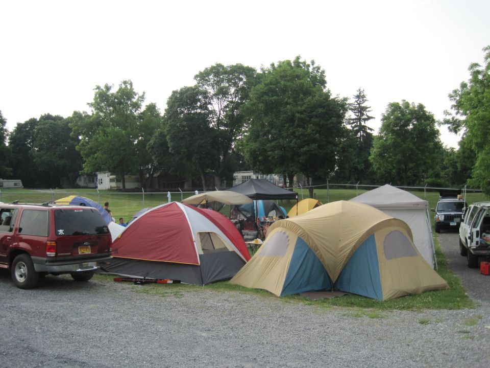 Red SUV parked next to tents at a campsite