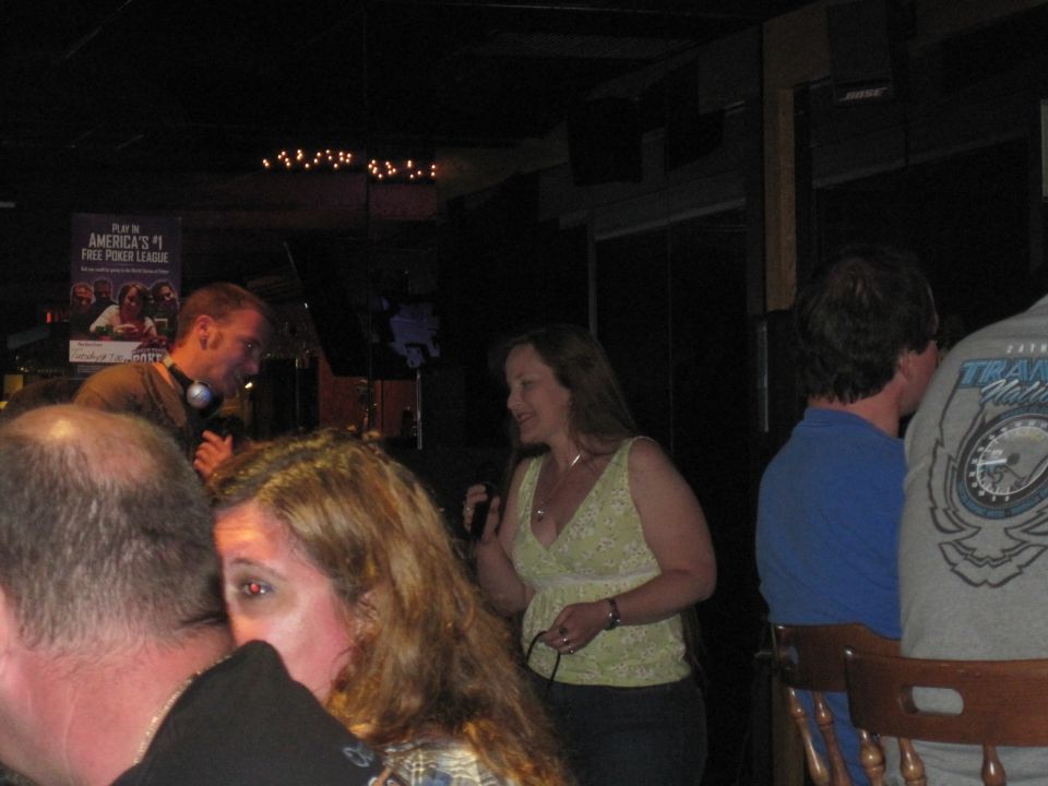 People in a bar with a poster for America's #1 Free Poker League