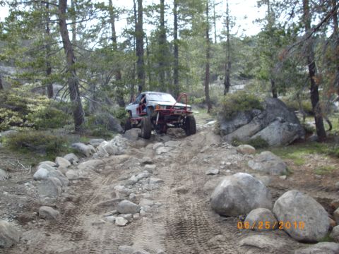 1982 Toyota 4Runner - A heavily modified pickup truck navigates a challenging, rocky path through a wooded area.