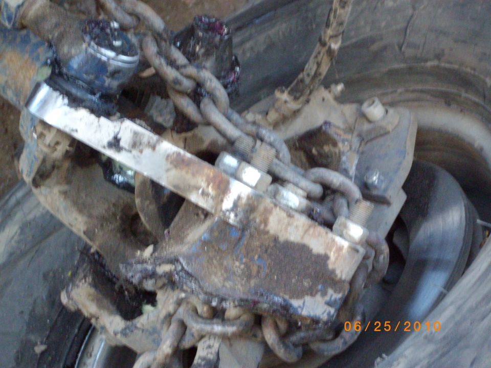 Close-up of rusty vehicle suspension parts and chains, with a tire visible
