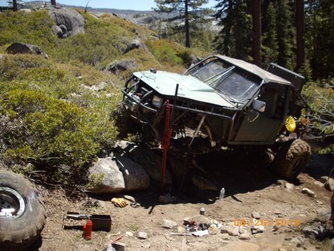 1982 Toyota Pickup/SR5 - A modified off-road vehicle is stuck on a rocky incline, with tools and a jack visible on the ground.