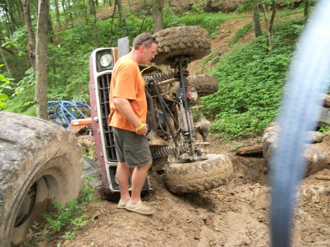 1978 Ford Bronco - Off-road vehicle overturned in mud, with a man observing the situation.