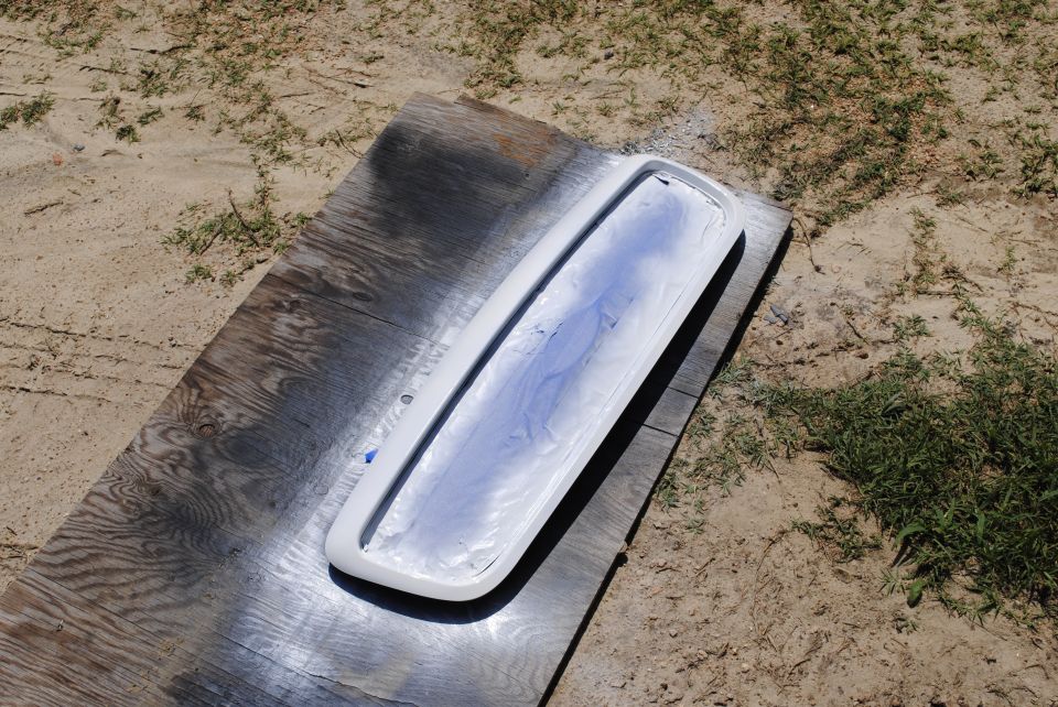 White grille with blue paint overspray on plywood outdoors