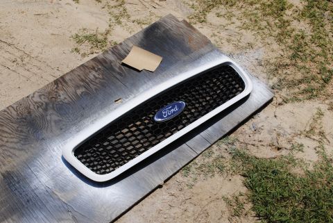2002 Ford Crown Victoria - A Ford grille is shown resting on wooden planks with a piece of sandpaper nearby.