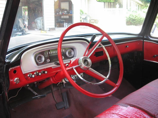 Classic pickup cab with red three-spoke steering wheel, red and white dash, bench seat