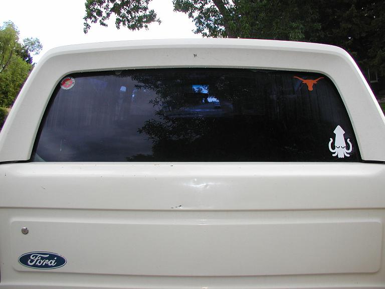 Rear window stickers, showing support for the National Rifle Association, the University of Texas Longhorns, and all things squid.