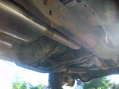 1986 Ford Bronco - The undercarriage of a vehicle shows the exhaust system and frame components.