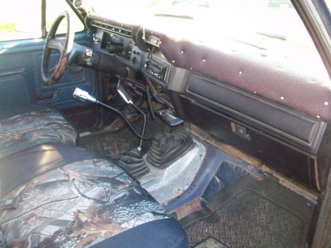 1986 Ford Bronco - Interior view of a truck, camouflage seat covers and dual stick shifters for transmission and transfer case.